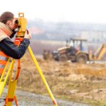 Surveyor looking through instrument at field